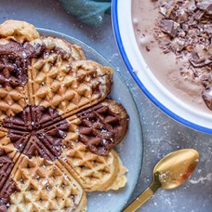 Ein Schokoladeneis mit Marabou-Stückchen in einer Schale, links daneben eine marmorierte Waffel