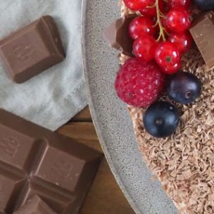 No-Bake-Schoko-Cheesecake mit Schokoraspeln, frischen Beeren und Marabou-Schokoladenstücken, serviert auf Teller