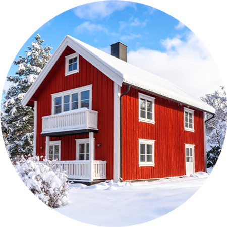 Ein rotes Holzhaus mit verschneitem Dach in einer verschneiten Winterlandschaft